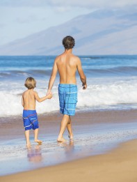 Happy father and son walking together at beach